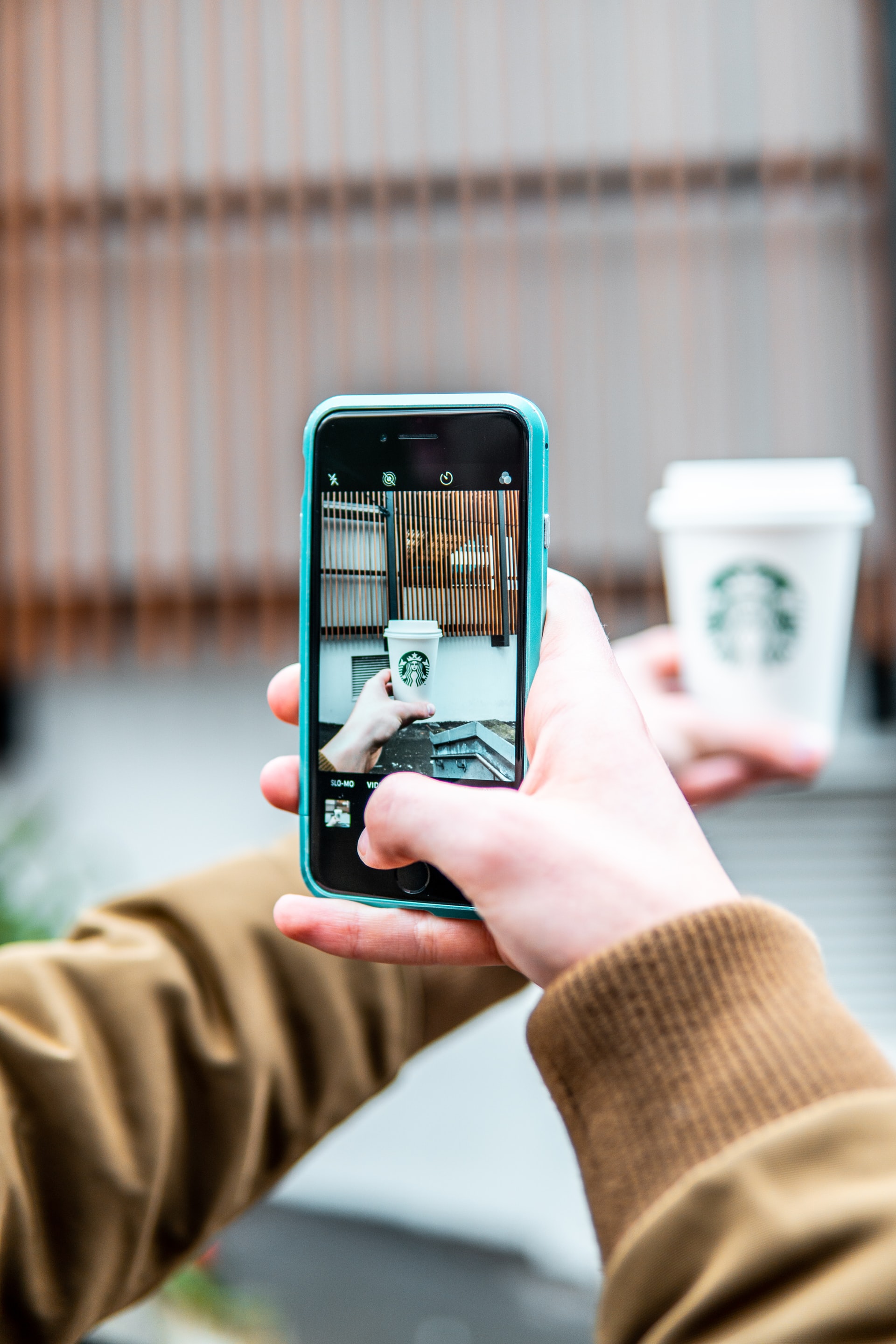 Person taking a photo of a Starbucks cup using a mobile phone
