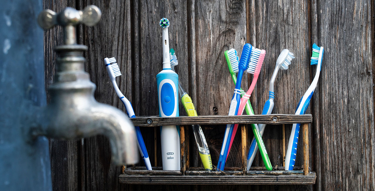 Toothbrushes lined up by a tap