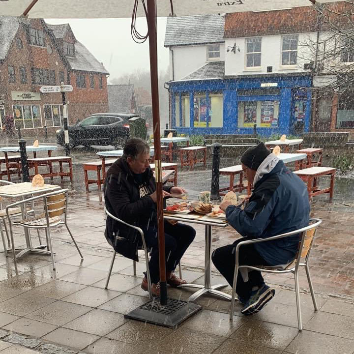 Two men enjoying a full english in the pouring rain