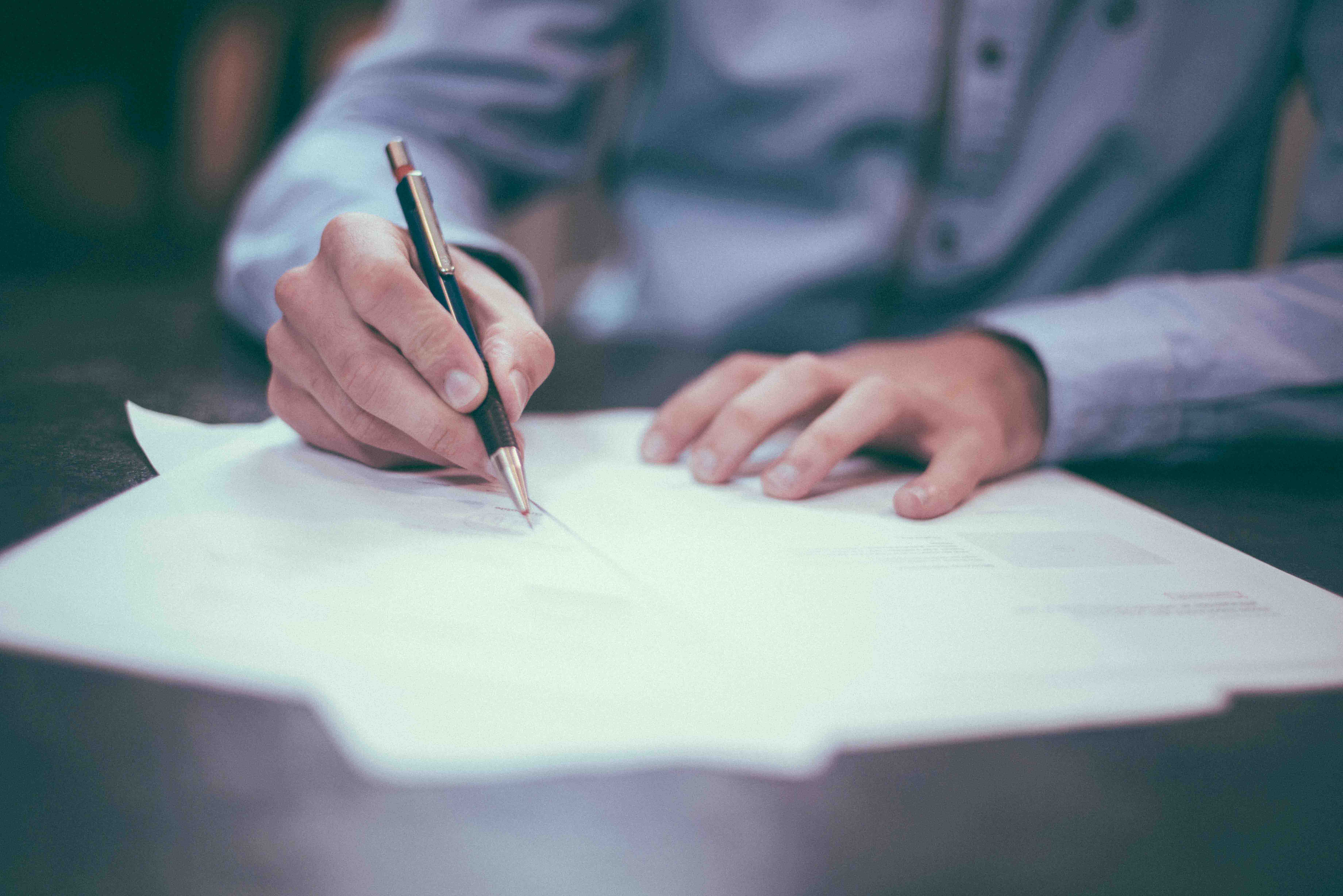 A person signing a piece of paper